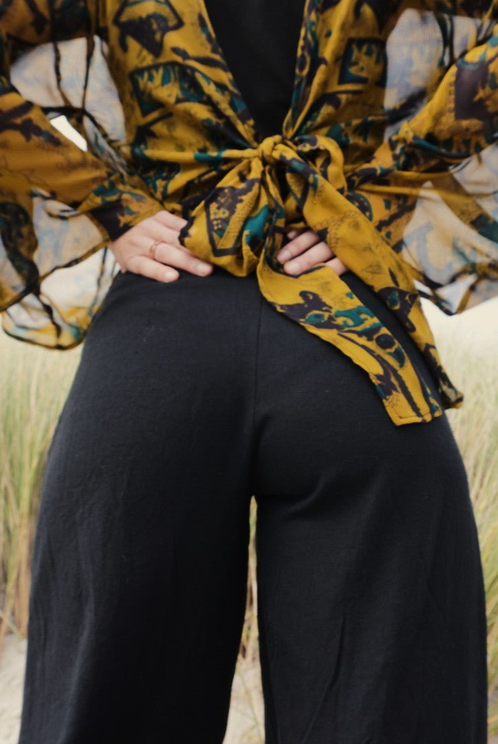 Person wearing a patterned yellow and black top with a blurred natural background