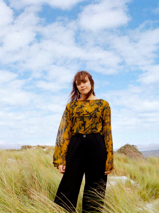 Person standing in a grassy field with a blue sky and clouds